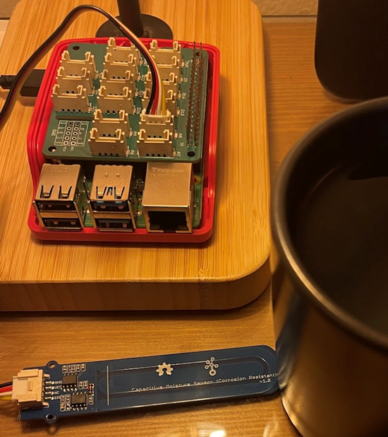 A raspberry pi setup with a hat that a moisture sensor is connected to.